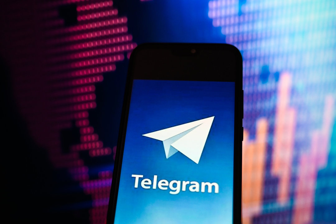 In this photo illustration a Telegram logo is displayed on a smartphone with stock market percentages in the background.