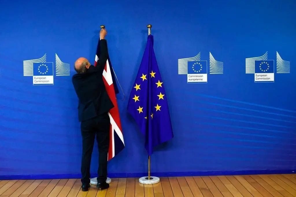 Un empleado coloca una Union Jack junto a una bandera de la Unión Europea en la Comisión Europea en Bruselas el 19 de junio de 2017, cuando Gran Bretaña iniciaba conversaciones formales para abandonar la UE. (John Thys / AFP vía Getty Images)