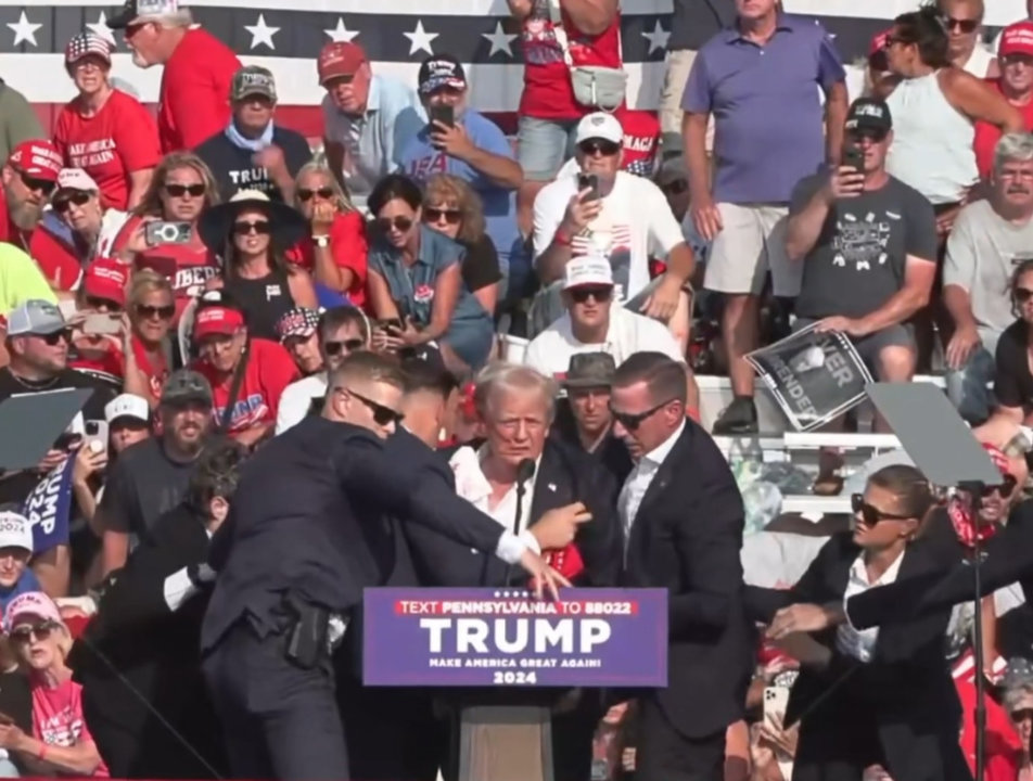 BUTLER, July 14, 2024  -- This video screenshot shows former U.S. President Donald Trump being helped off the stage at a rally in Butler, Pennsylvania of the United States after what sounded like gunshots rang out through the crowd, July 13, 2024.
  Video footage showed that Trump was making a speech when popping sounds rang out over the rally. Screams could be heard in the crowd, and Trump was swiftly escorted off the stage by Secret Service agents.
  Blood could be seen on the side of his head and his ear. He was quickly escorted into a vehicle, and his motorcade has left the venue.
  Trump is currently safe and is expected to survive, NBC News reported, quoting senior law enforcement officials.
  The shooting incident at Trump's rally in Pennsylvania is being investigated as attempted assassination, local media reported on Saturday night, citing law enforcement officials.,Image: 889566316, License: Rights-managed, Restrictions: , Model Release: no, Credit line: Hu Yousong / Xinhua News / ContactoPhoto